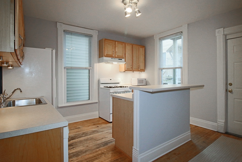 an empty kitchen with white appliances and wooden cabinets
